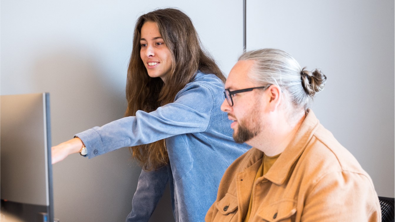 twee collega's die samen naar een beeldscherm kijken